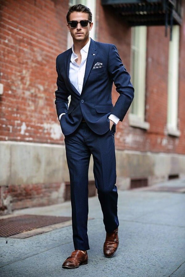 Men's two button navy suit style worn with a white shirt and brown shoes
