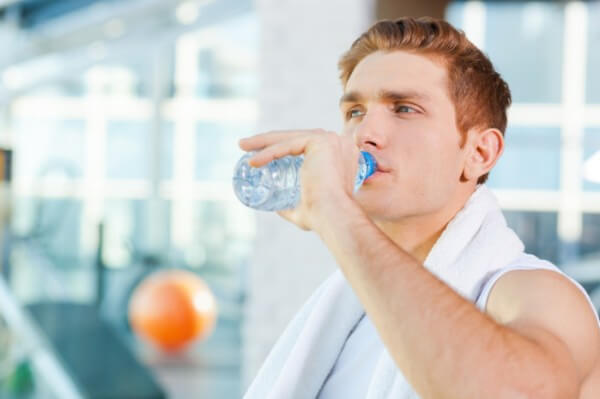 Guy drinking a bottle of water after taking shower