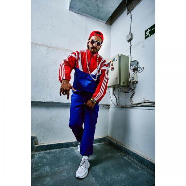 Ranveer Singh wearing blue and red Adidas Originals , a red baseball cap and a long chain around his neck.