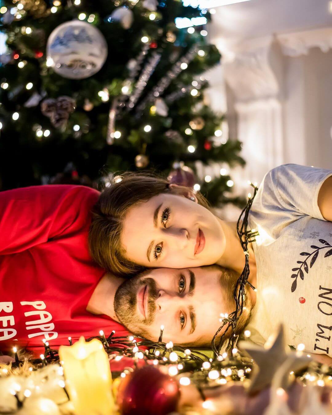 Christmas Photoshoot Ideas for Couple Glowing Faces In Lights - Head On Head Pose