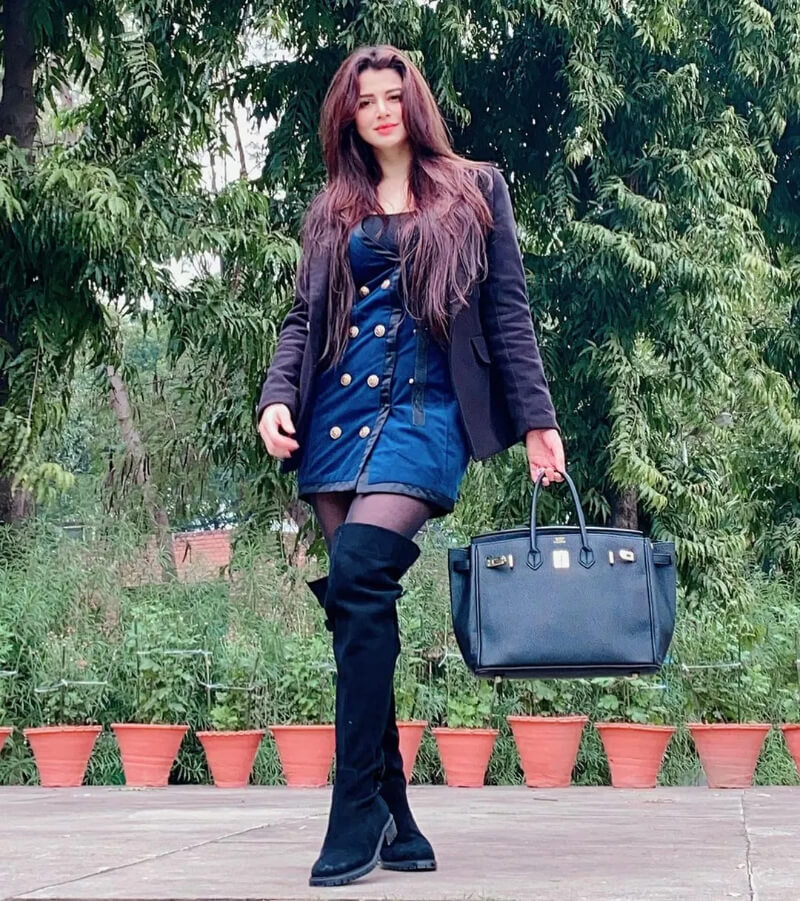 Bollywood  Actress Kainaat Arora in a blue dress with a black blazer and a pair of thigh-high boots.
