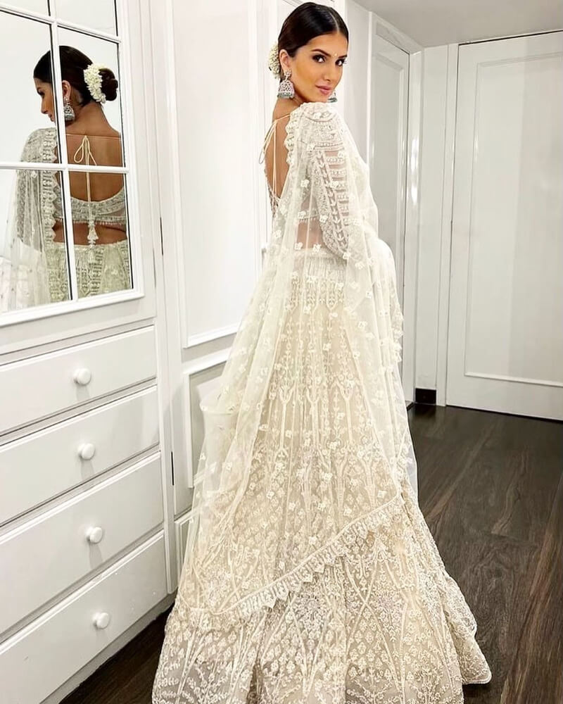 Tara Sutaria in a voluminous all-white lehenga set with a full-sleeved fan-panel blouse and dupatta