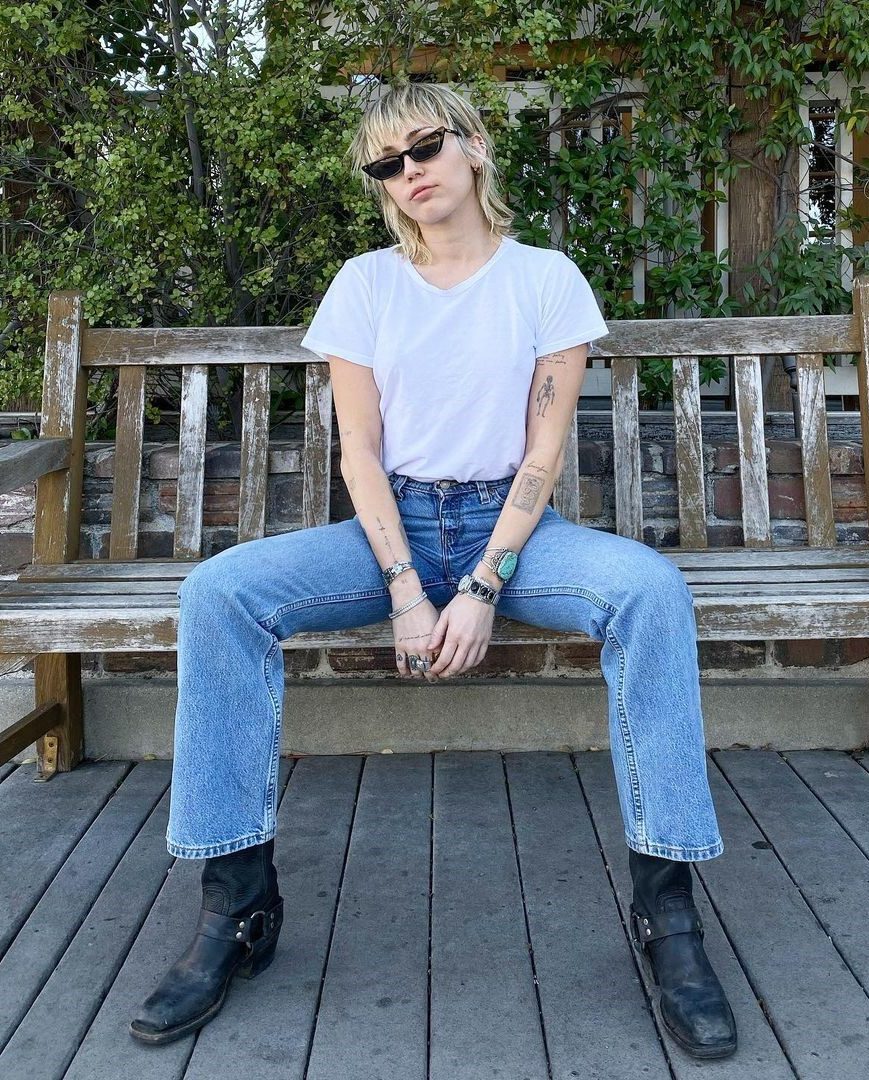 Miley Cyrus In A White Tee Paired With Denim Jeans & Black Boots