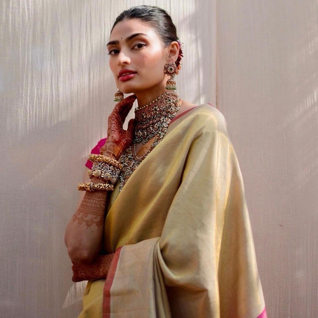 Athiya Shetty is a traditional Kannada bride as she opted for a plain gold handwoven tissue kanchipuram saree with a fuchsia pink blocked pallu from Madhurya 