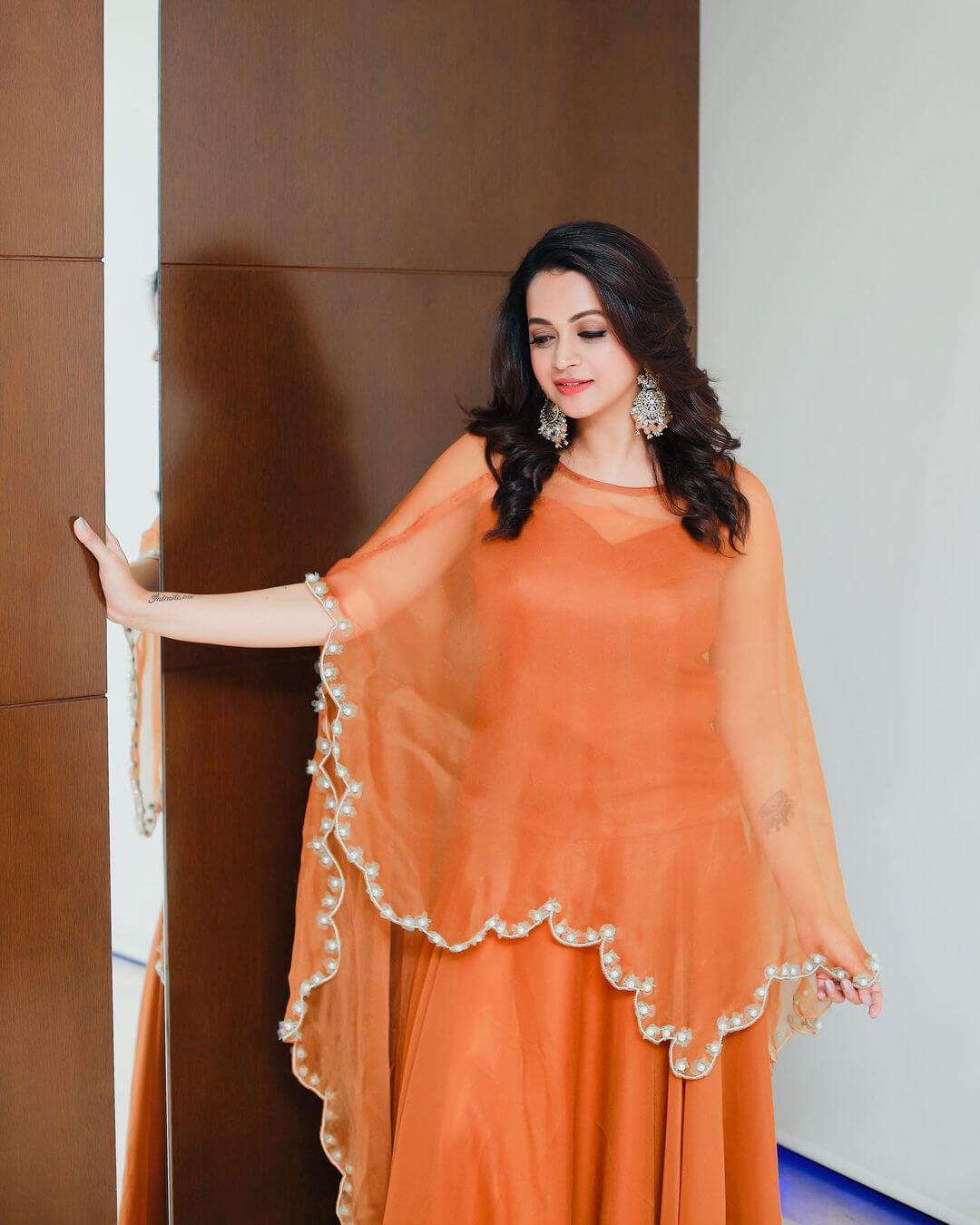 Bhavana Menon In Orange Gown With Pearl Border Ponchu