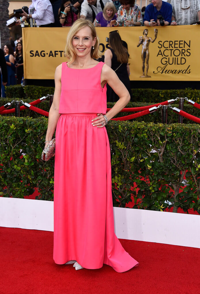Amy Ryan in a pink top And skirt by Honor with a metallic clutch