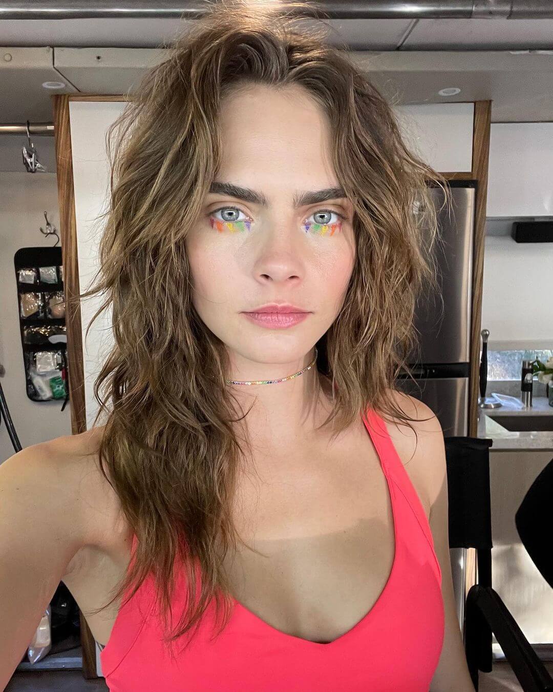 Cara Delevingne Rocks the 70s Shag Look with Colorful Eye Makeup and a Coral Pink Top