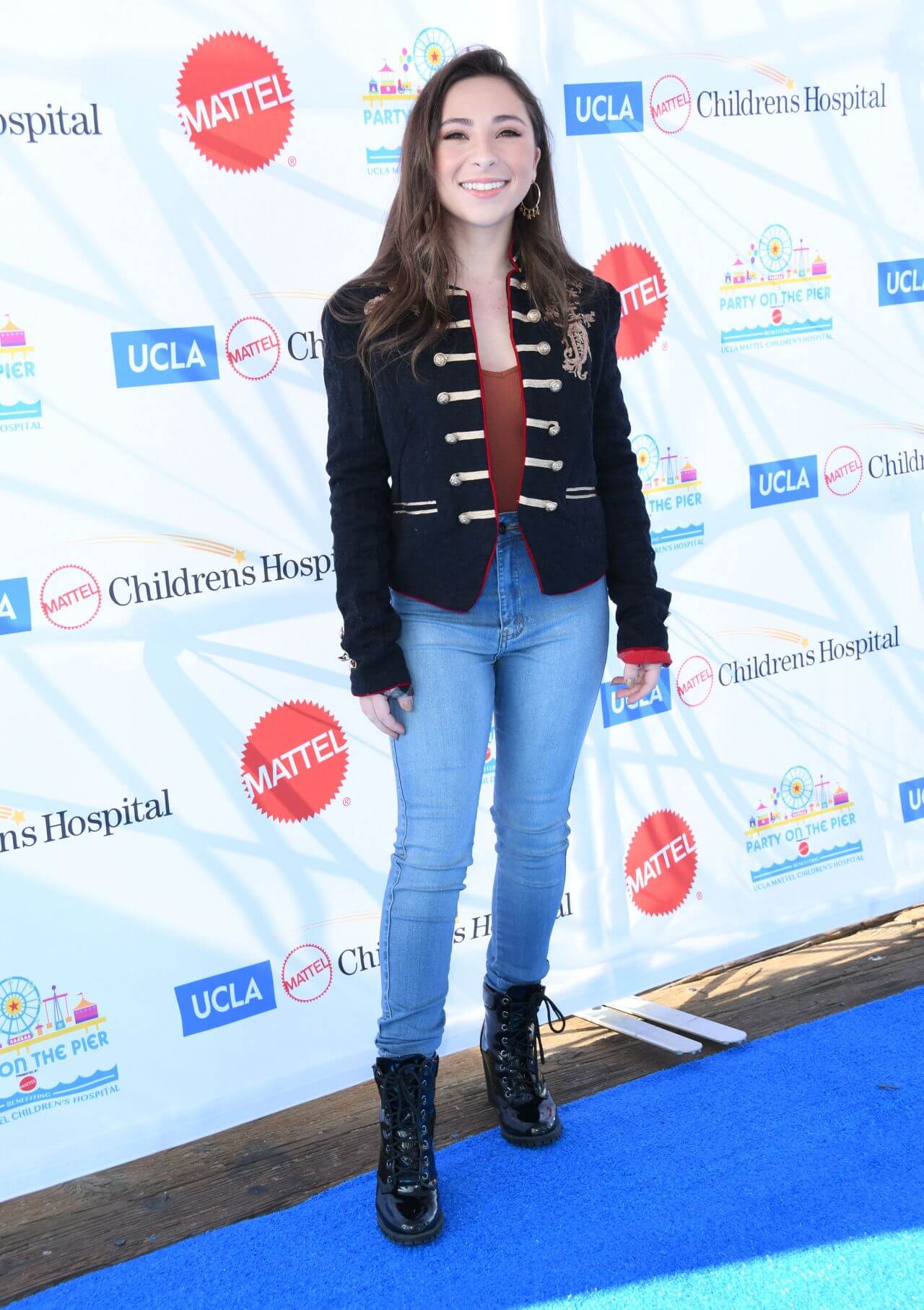 Ava Cantrell In Black Coat Under Top With Blue Denim Jeans At “Party on the Pier” in Santa Monica