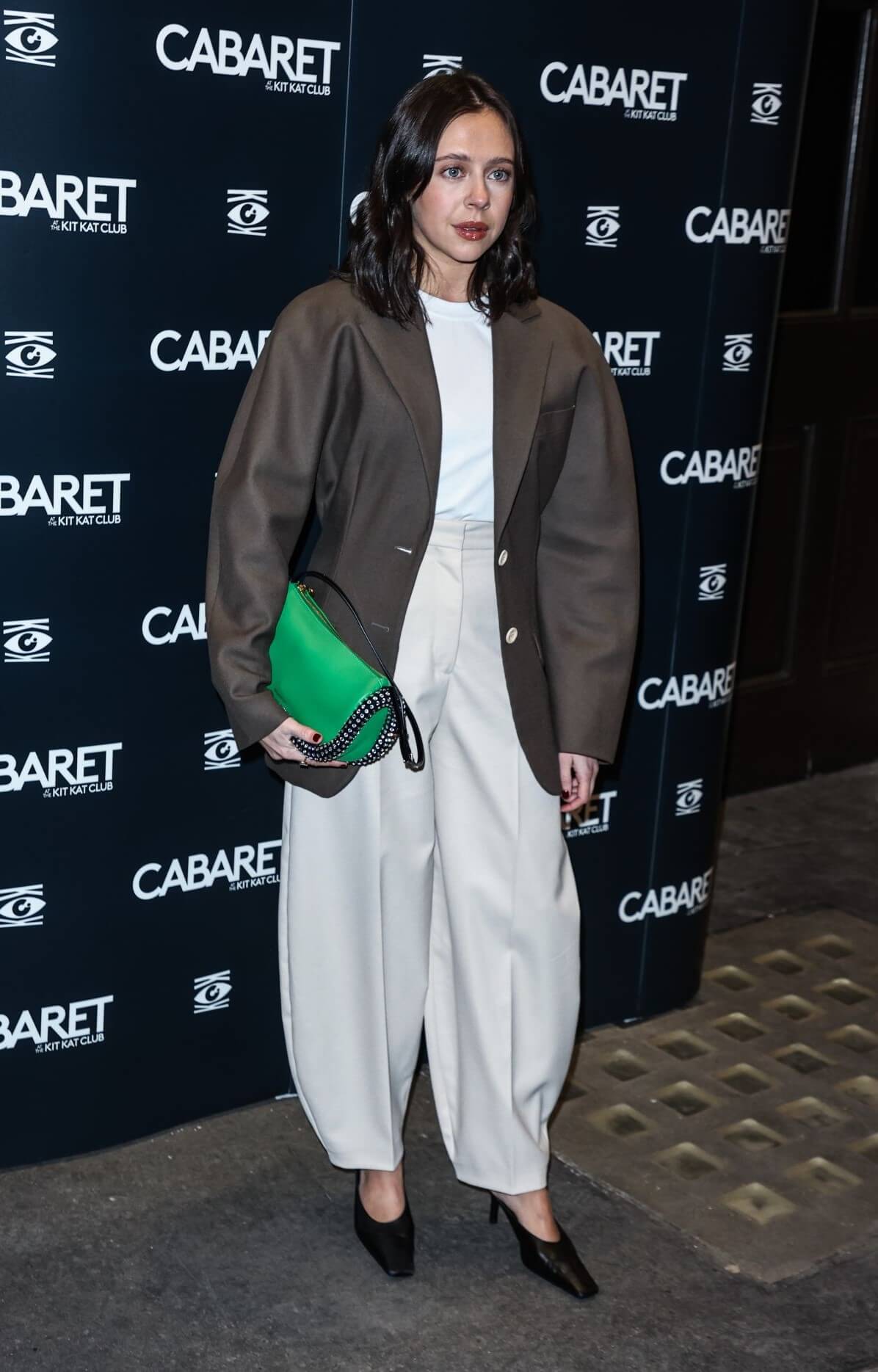 Bel Powley  In Deep Brown  Coat Under White T-shirt With Baggy Pants At“Cabaret” Gala Night in London