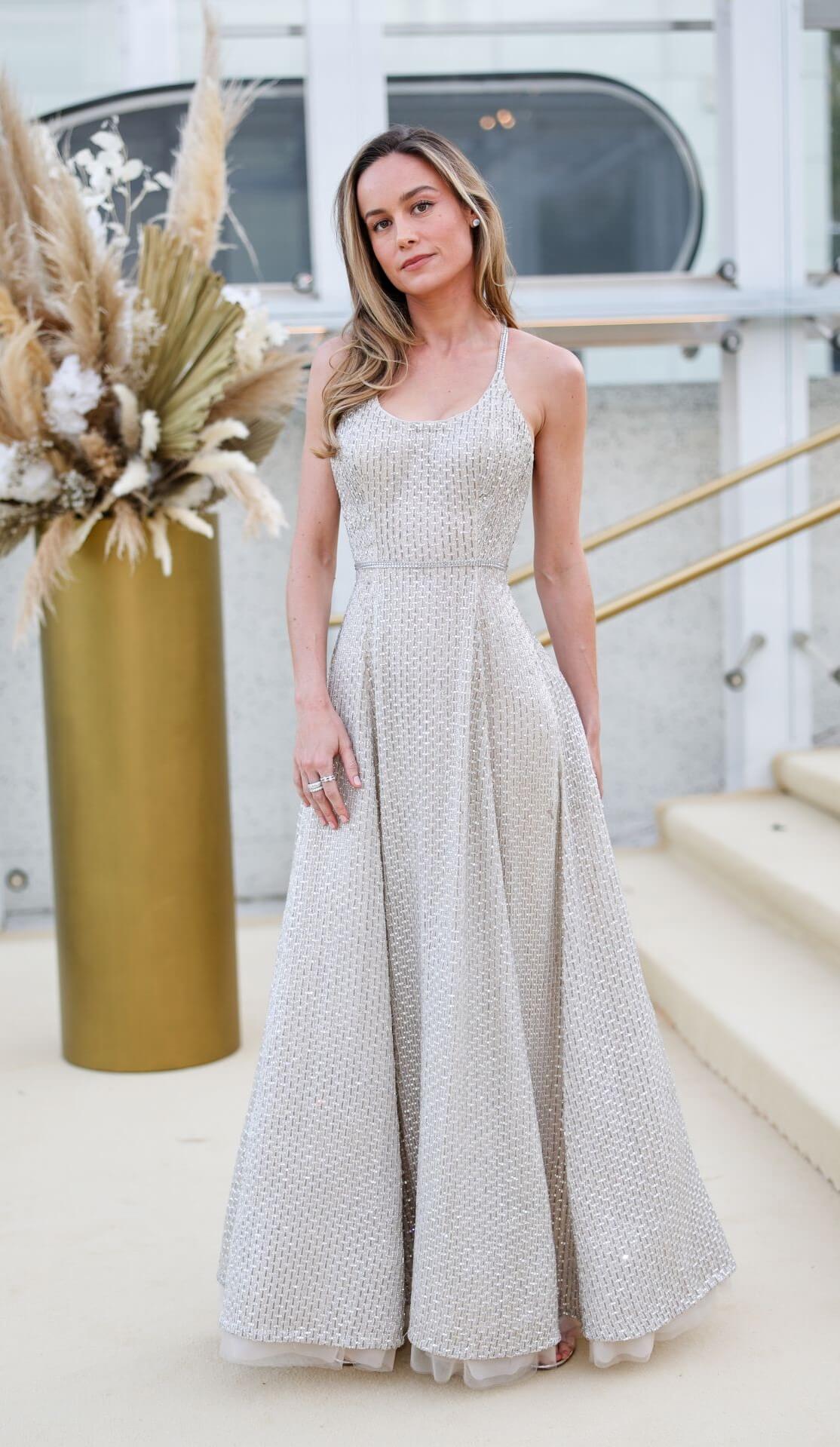 Brie Larson  In White Shiny Strap Sleeves Long Flare Gown At Gold House 2nd Annual Gold Gala: Gold Bridge in Los Angeles