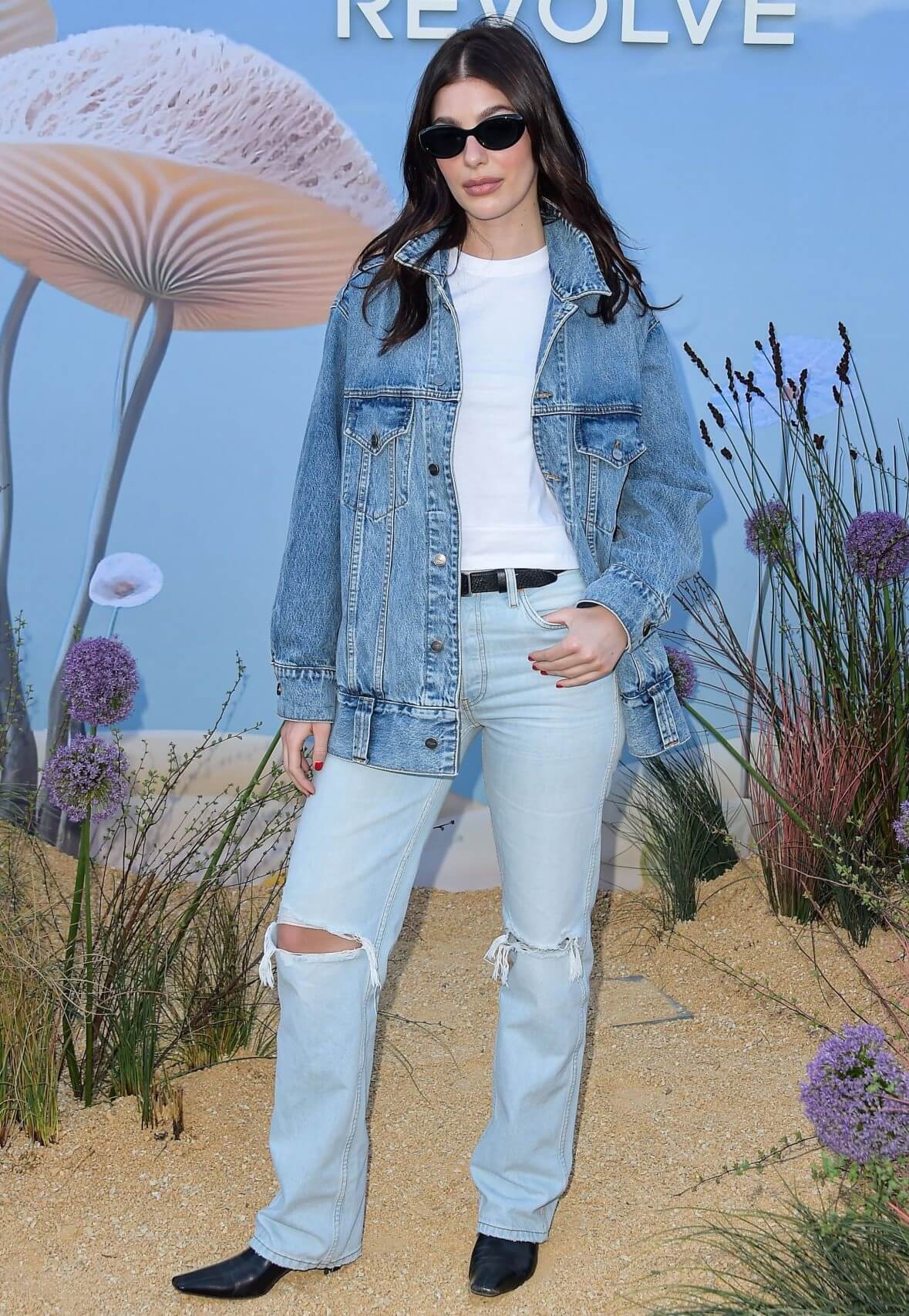 Camila Morrone  In Blue Denim Jacket Under White T-shirt With Damage Jeans At Revolve Festival in Indio