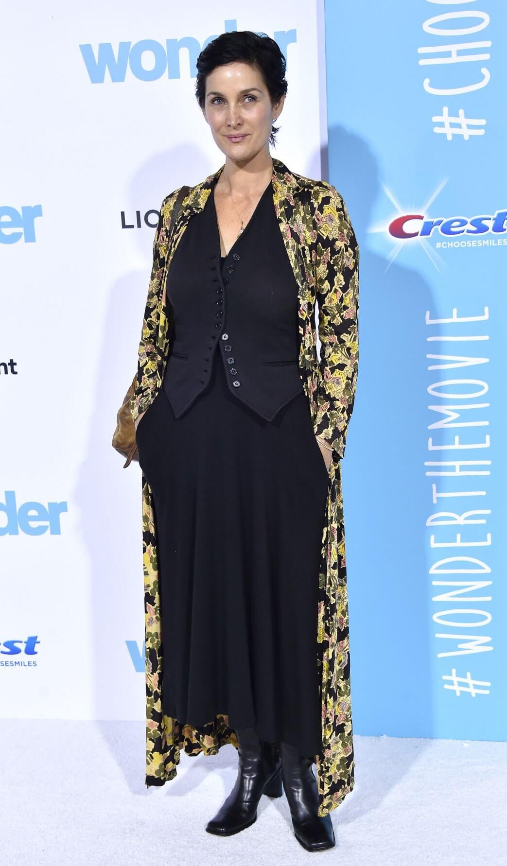 Carrie-Anne Moss  In Yellow Printed Long Shrug Under Black Top With Long Skirt Outfit At“Wonder” Premiere in Westwood