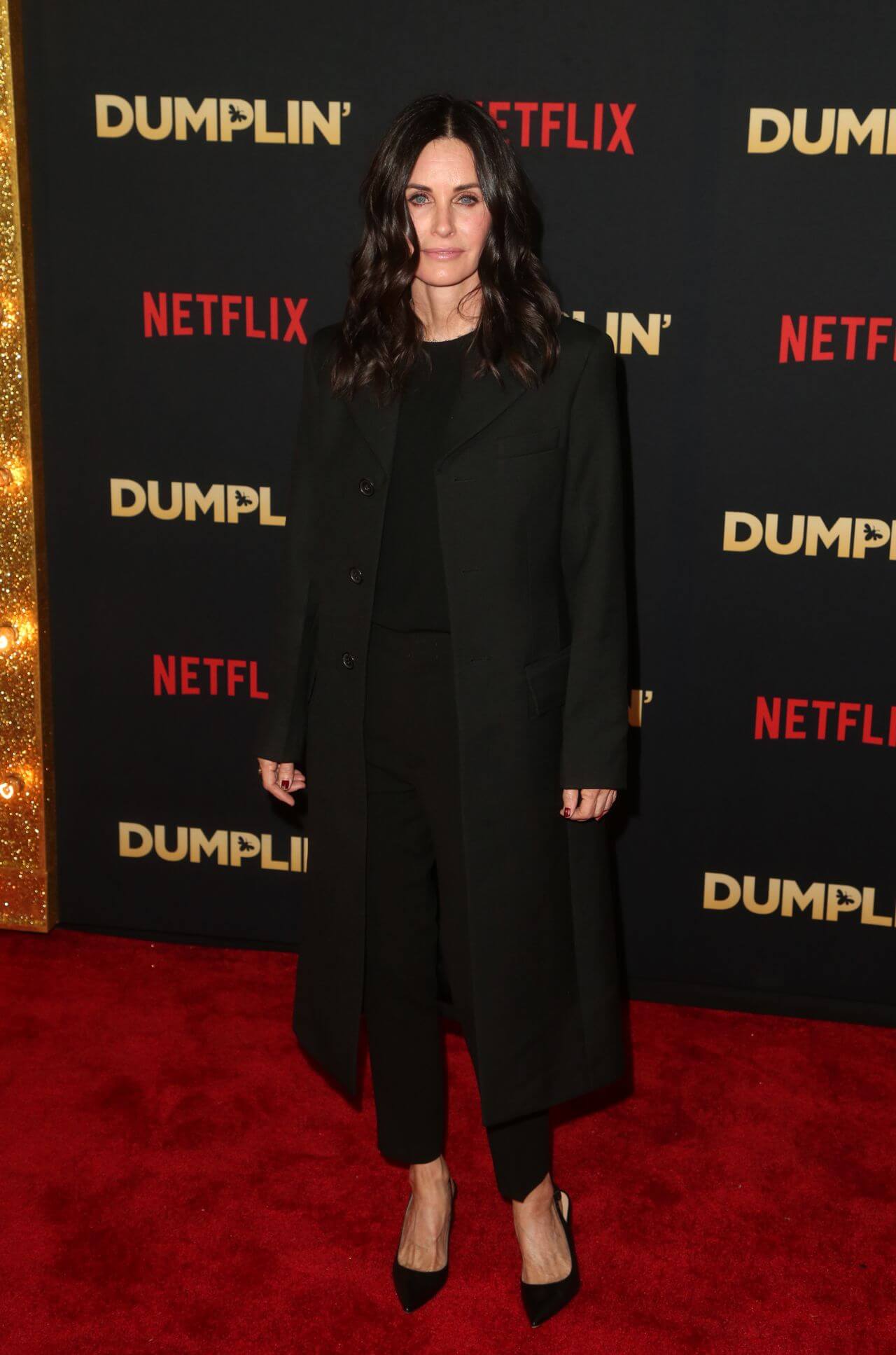 Courteney Cox  In Long Overcoat Under Black Dress At “Dumplin” Premiere in Hollywood