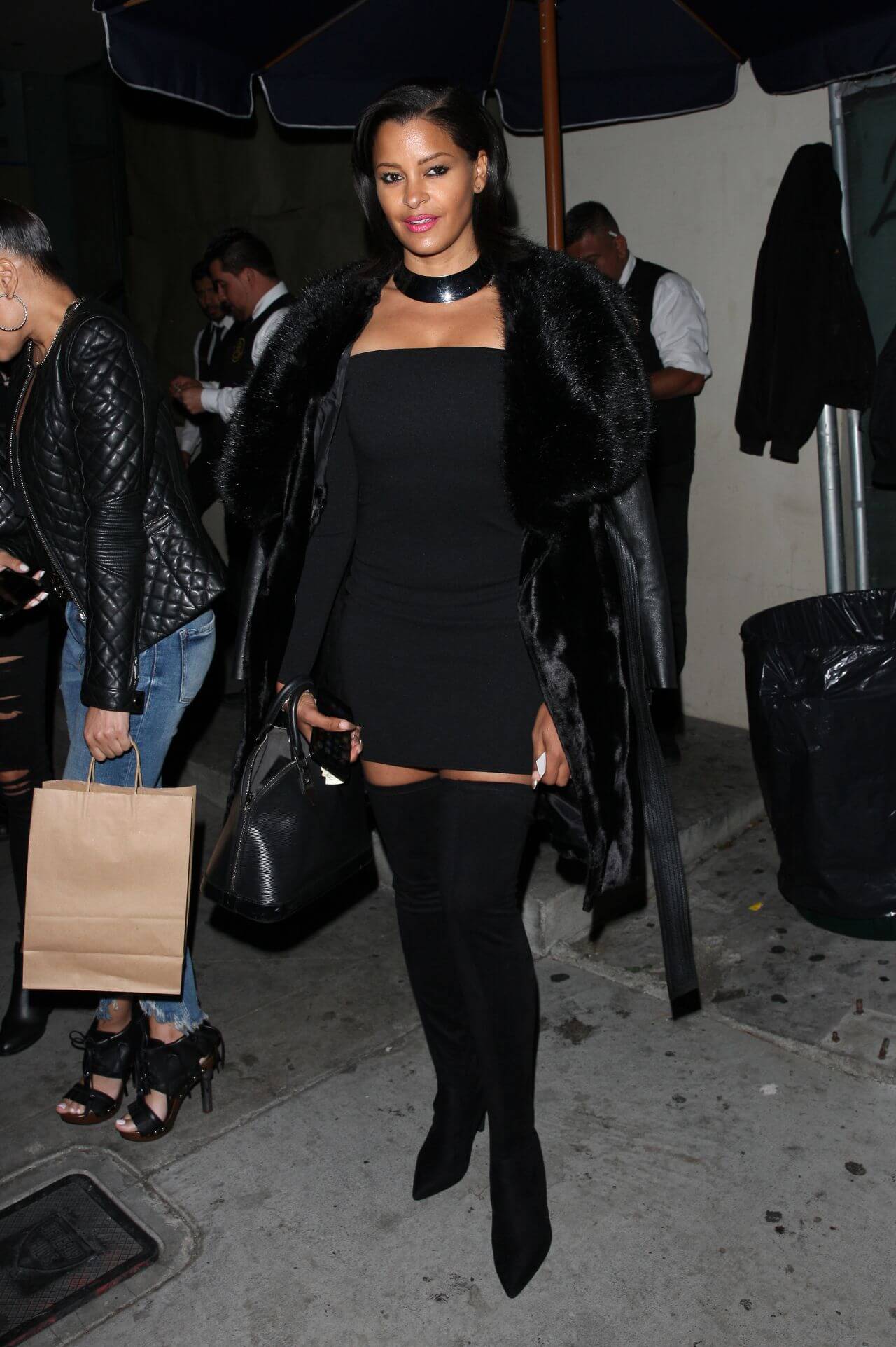 Claudia Jordan In a Black Fur Jacket Under a Mini Dress With Long Boots